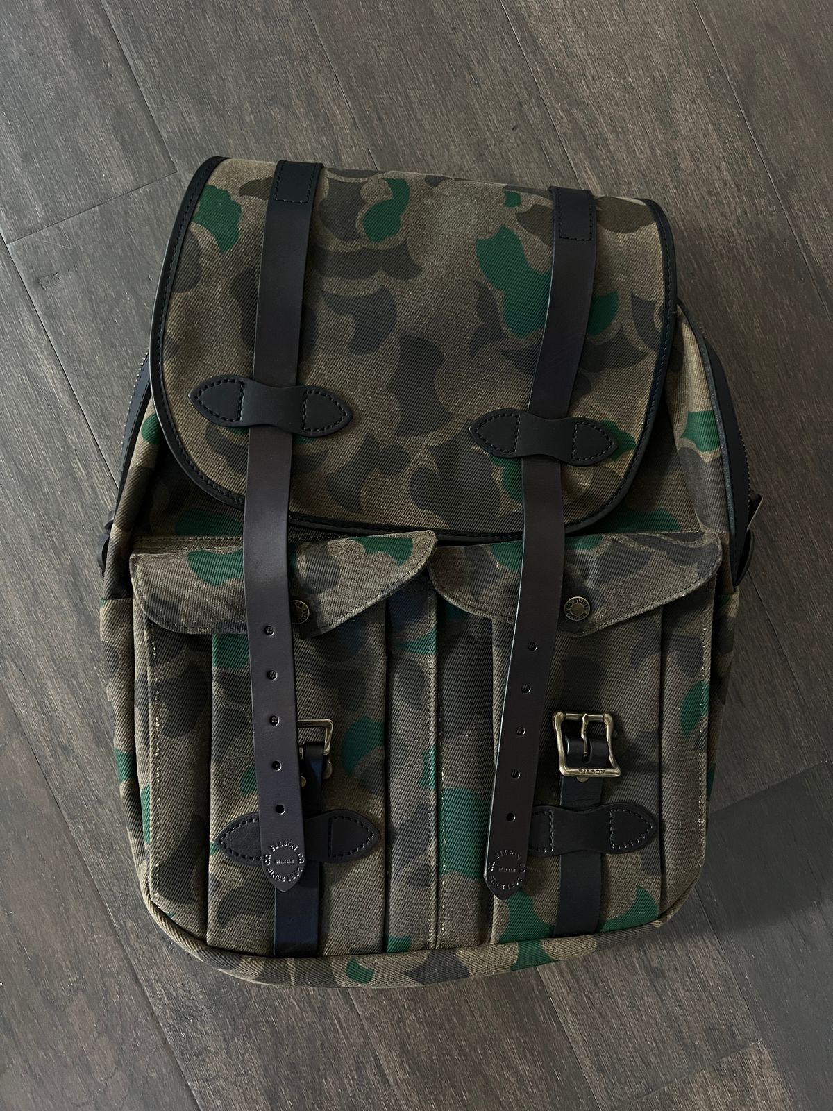 Photo by Texas_denim88 on October 29, 2025 of the Filson Large Rugged Twill Rucksack Shrub Camo in Saddle-grade Vegetable Bridle Leather & Heavily Waxed Rugged Twill.